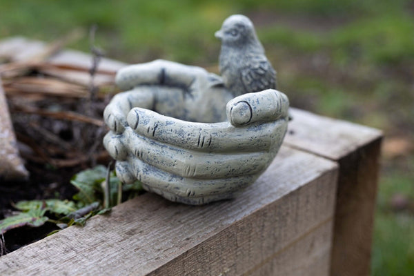Stone effect bird bath placed in a flower bed