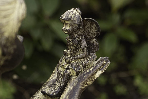 Resin statue of a sitting girl holding a fairy