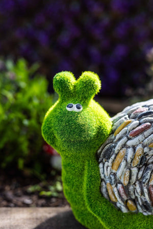 Stone effect snail positioned amongst garden plants