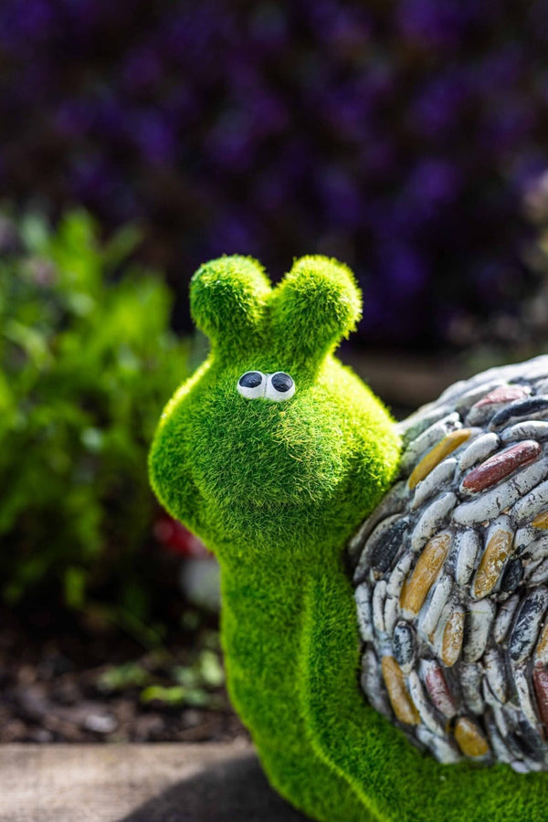 Stone effect snail positioned amongst garden plants