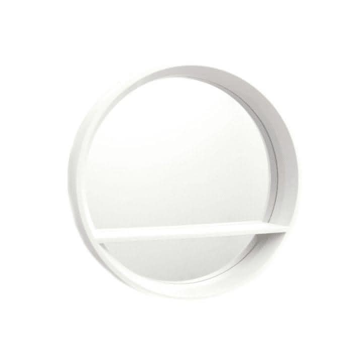 Round white mirror on a green wall with a living room reflection.