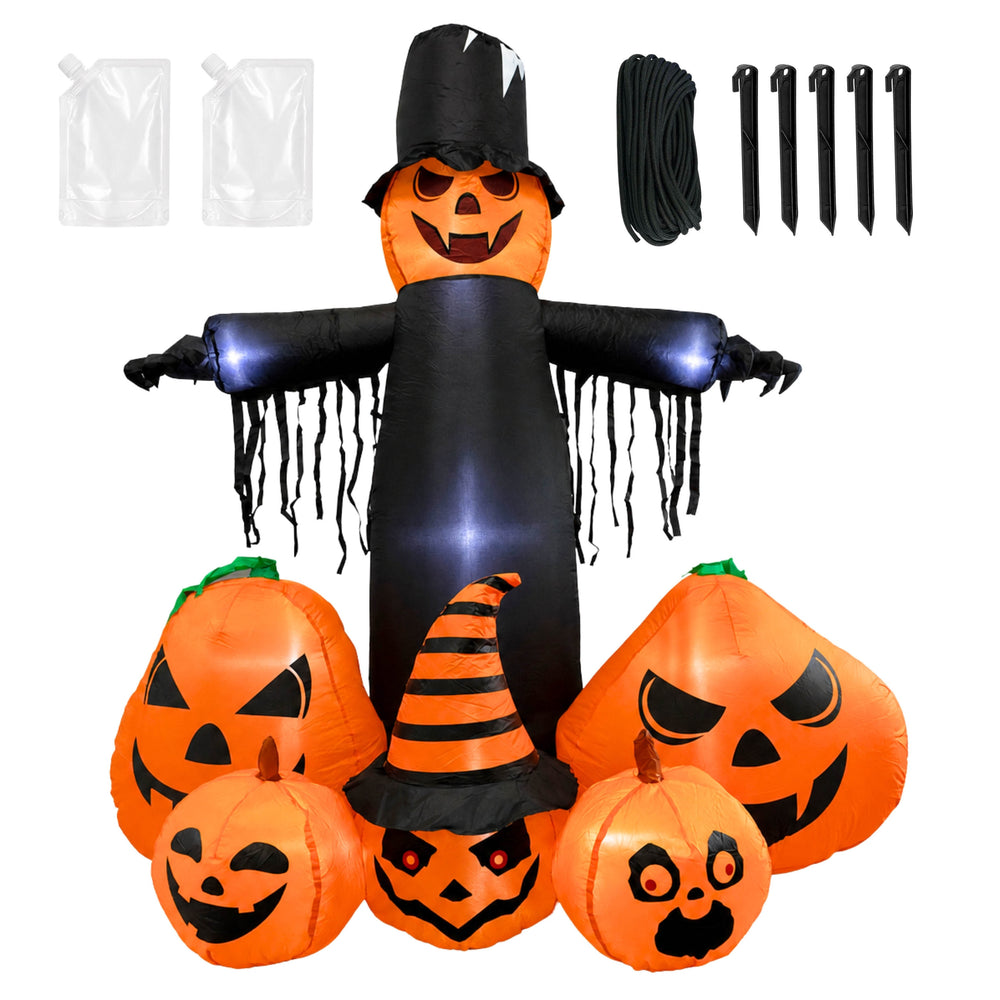 An inflatable Halloween yard decoration set displayed on a lawn in front of a house. The set includes a tall black-and-orange scarecrow with glowing blue arms and five carved jack-o'-lantern pumpkins in front, including one with a small orange-and-black striped witch hat.