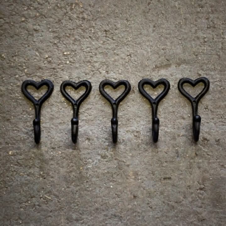 Five black heart-shaped hooks on a textured brown surface 