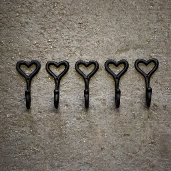 Five black heart-shaped hooks on a textured brown surface 