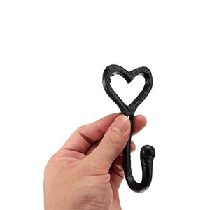 Hand holding a black heart-shaped hook against a white background