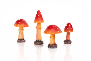 Red garden fungi ornaments displayed beside flowers