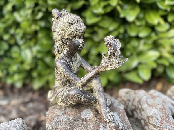Sitting girl fairy ornament positioned in a flower bed