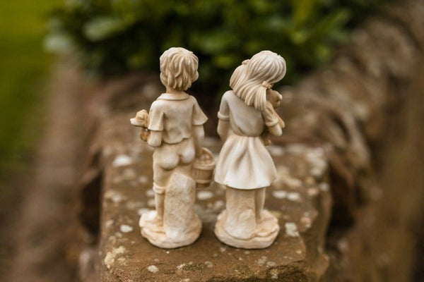 Stone effect figures positioned beside garden plants