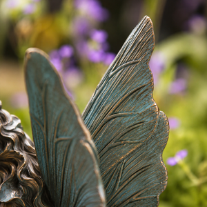 Decorative winged figure sitting beside flowers
