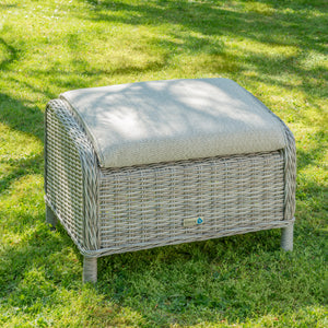 Wicker ottoman with a cushion on a grassy lawn