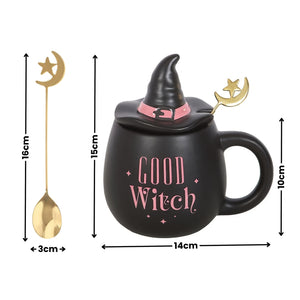Black witch-themed ceramic mug with a pointed hat lid, pink 'Good Witch' text, and a gold spoon with a crescent moon and star handle, shown with height and width dimension callouts on a white background.